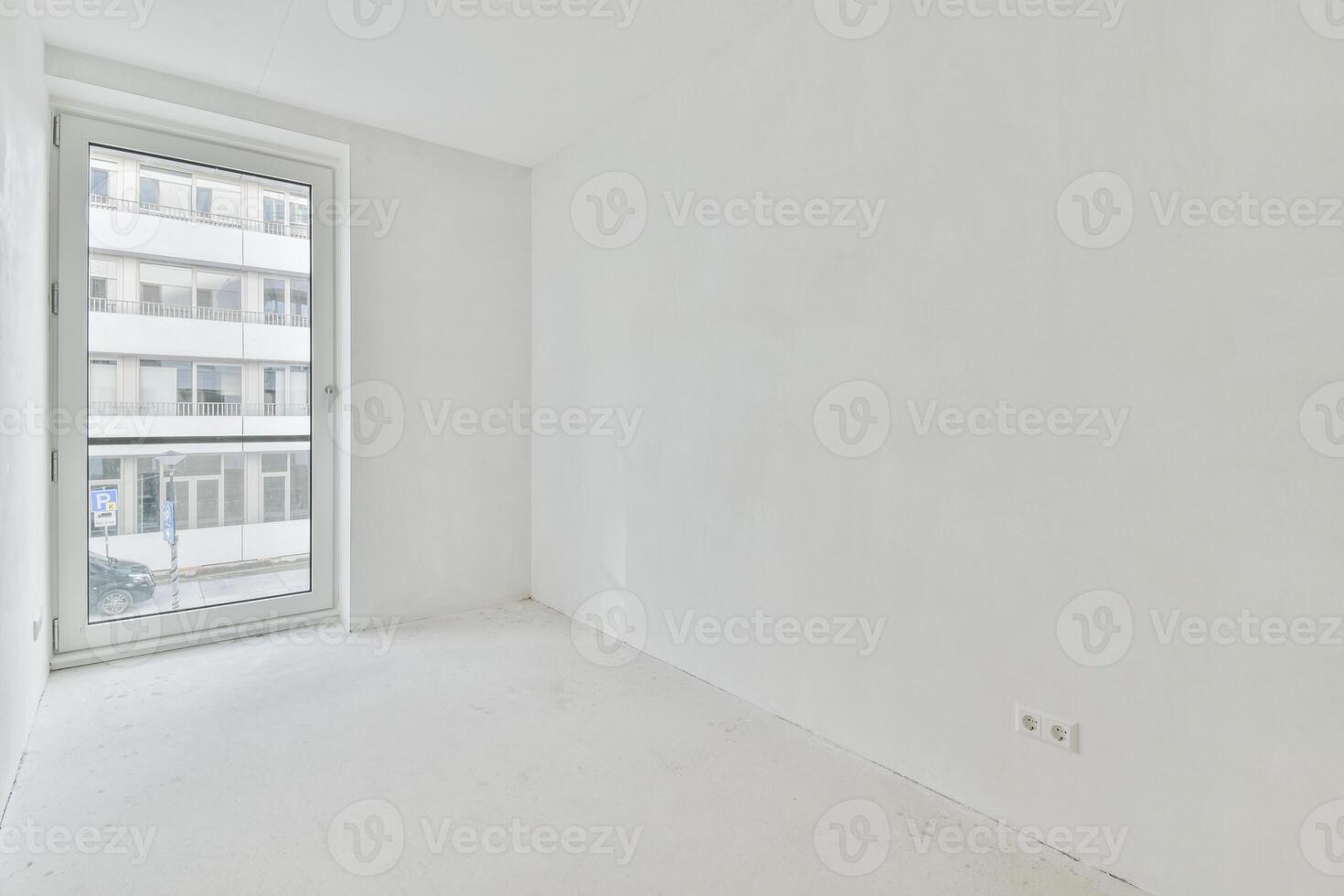 An empty room with a large window and white walls photo