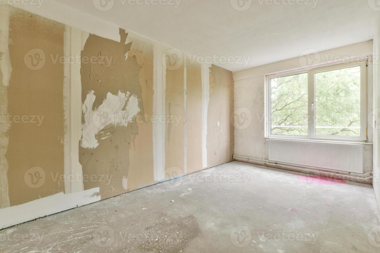 An empty room with a wall covered in drywall photo