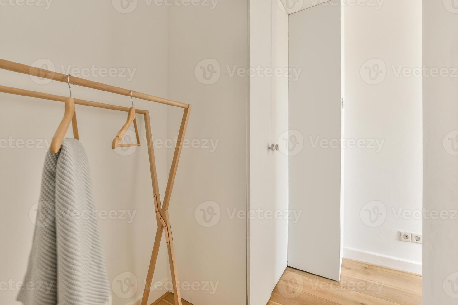 A white closet with a wooden rack and a towel photo