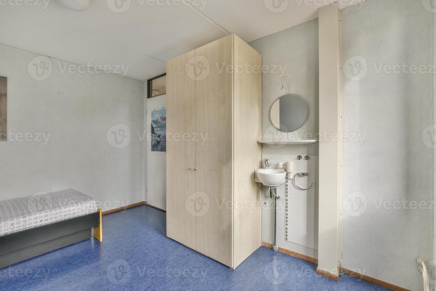 A small room with a bed, a sink and a mirror photo