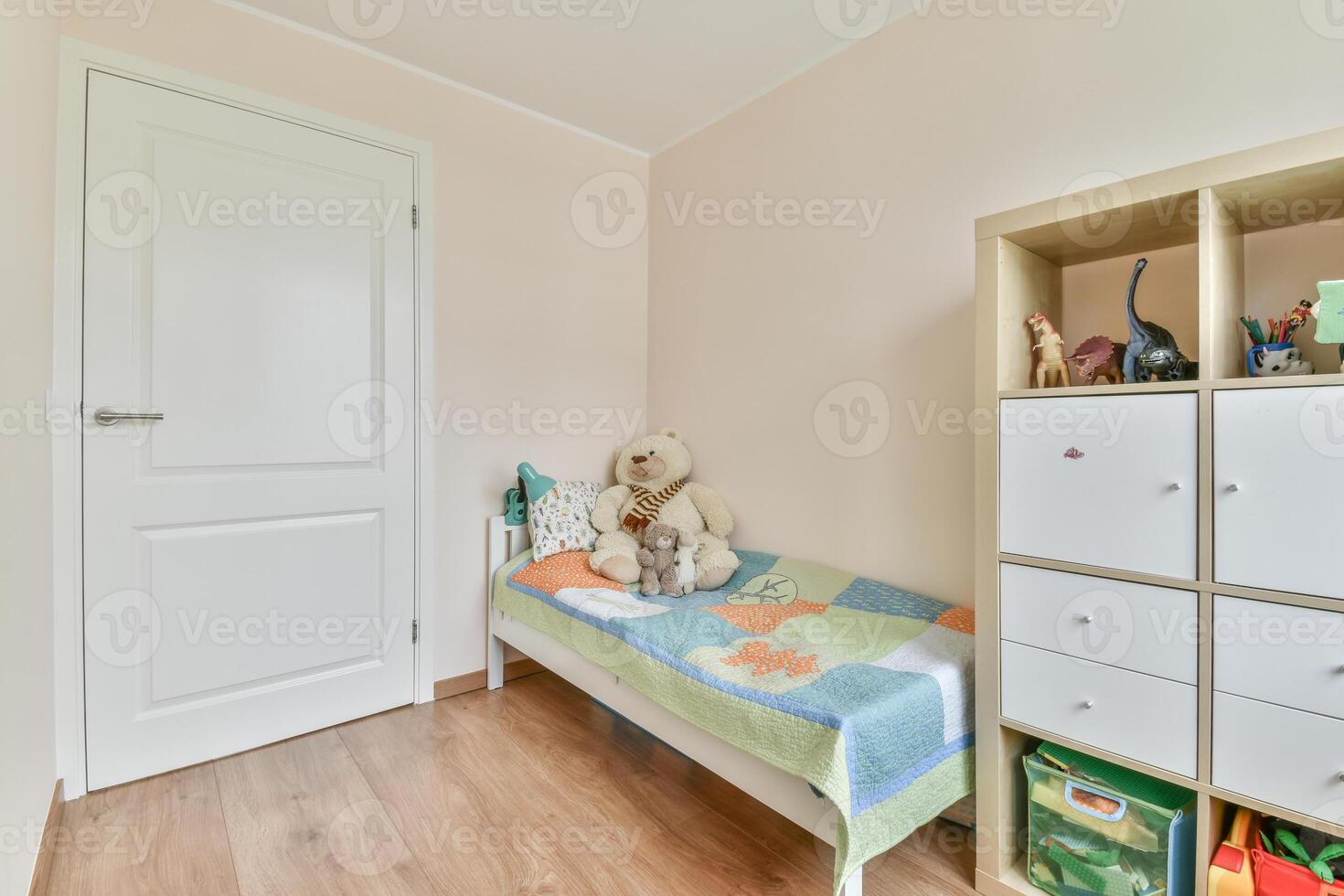 A small room with a bed, a toy box, and a door photo