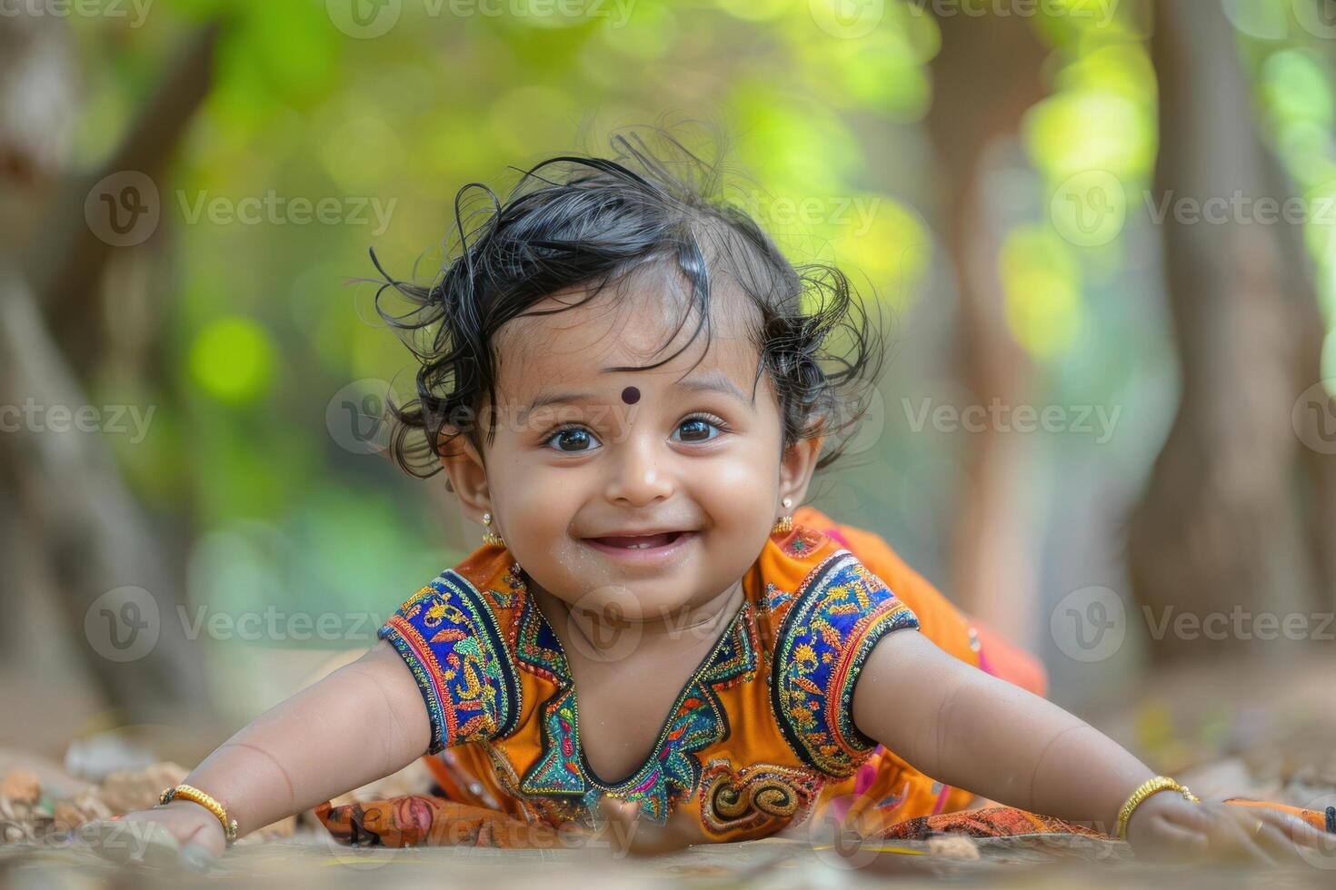 A baby girl in an orange dress laying on the ground photo