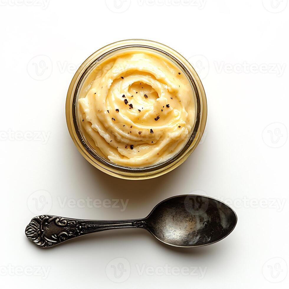 Small jar of garlic aioli with a spoon beside it arranged on a clean white background creamy and smooth photo