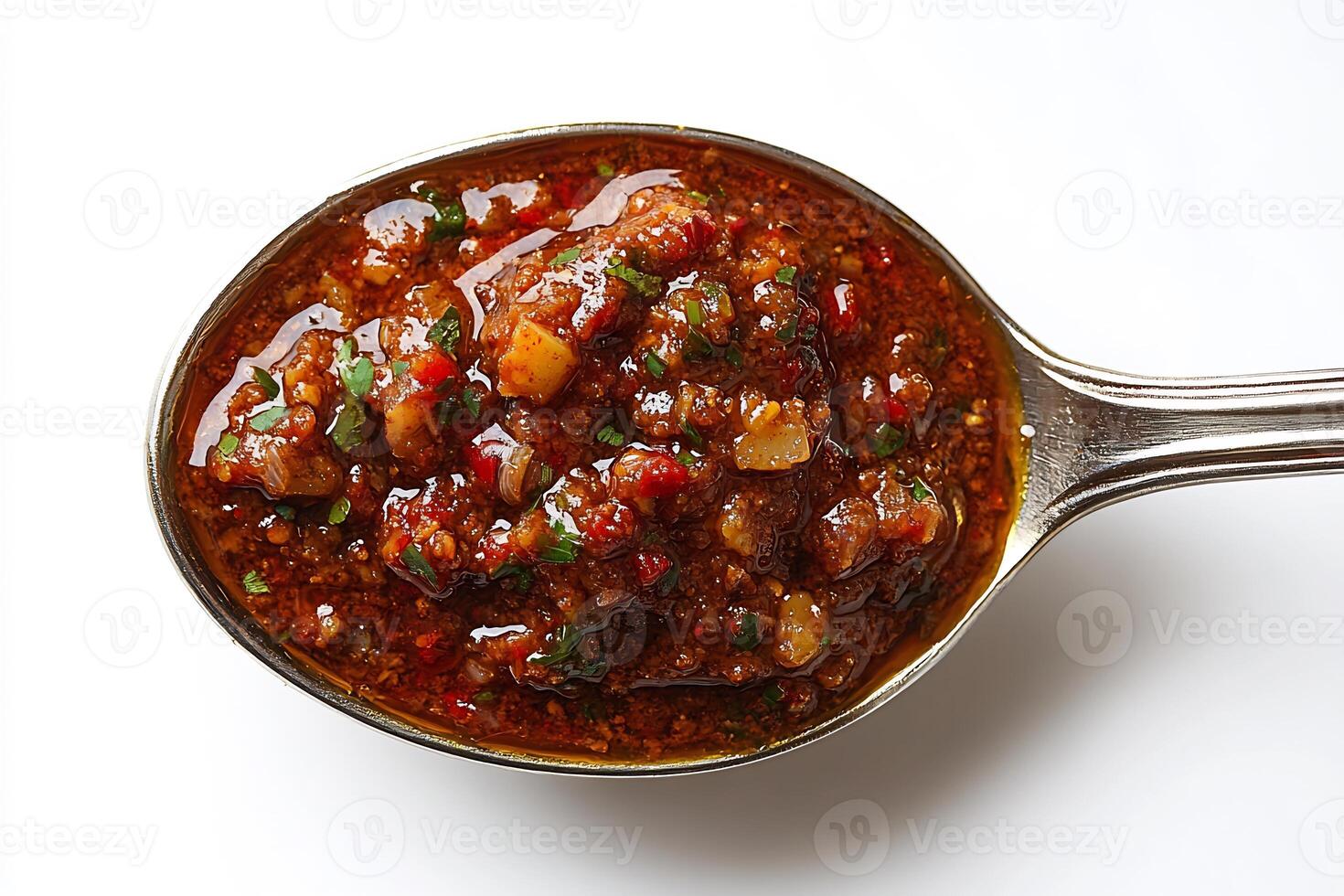 Spoonful of rich spicy curry sauce placed in the center of a white background showing texture and boldness photo