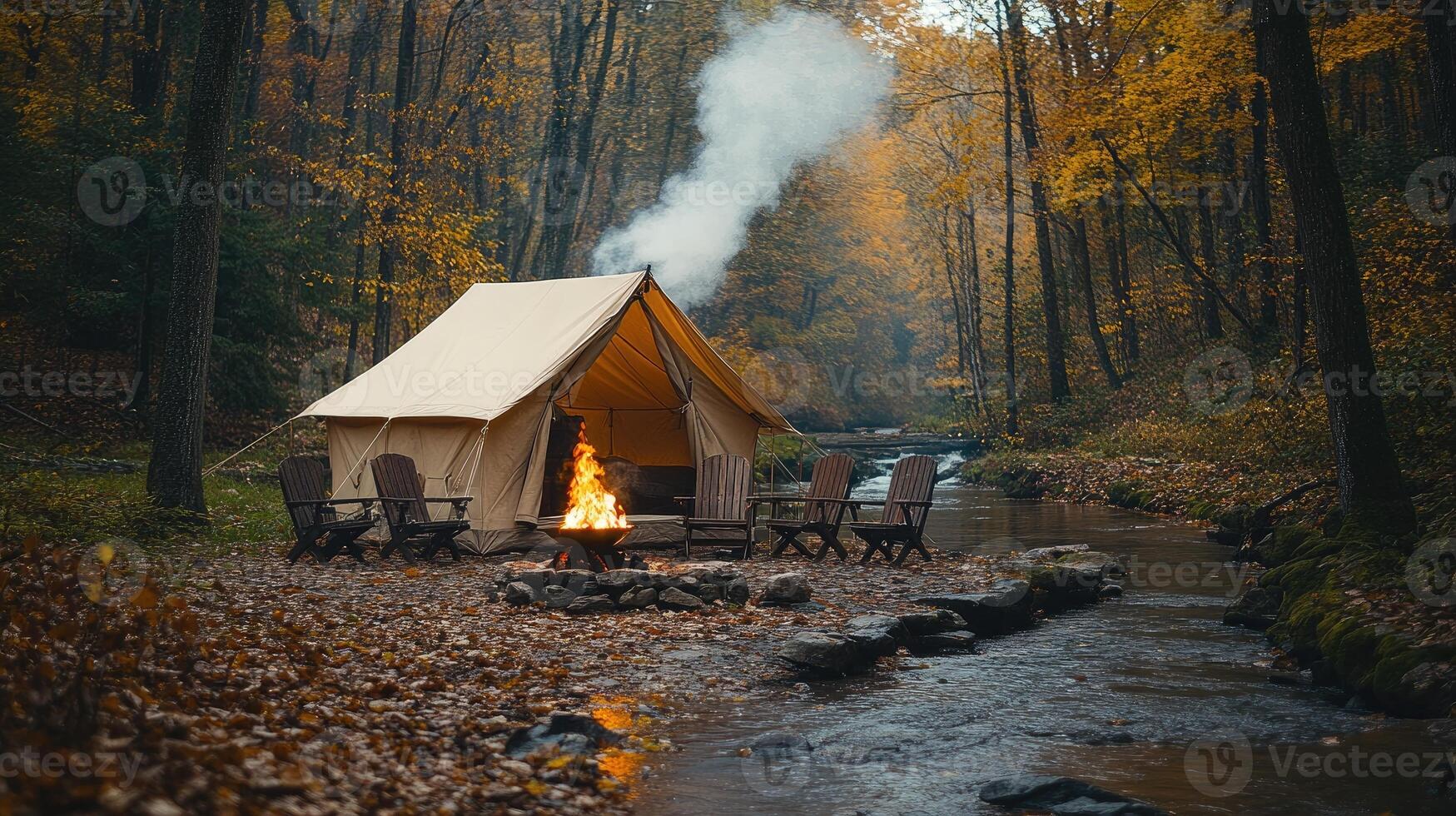 Smoke rising from campfire in front of tent near river in autumn forest photo