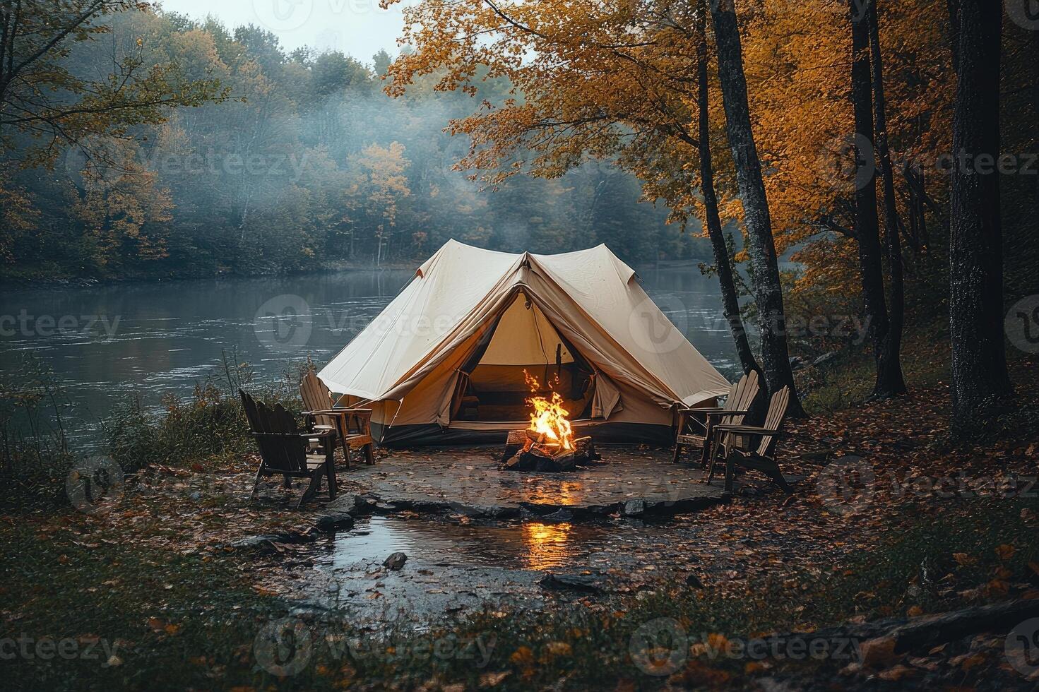 Illuminated tent camping by misty river in autumn forest photo