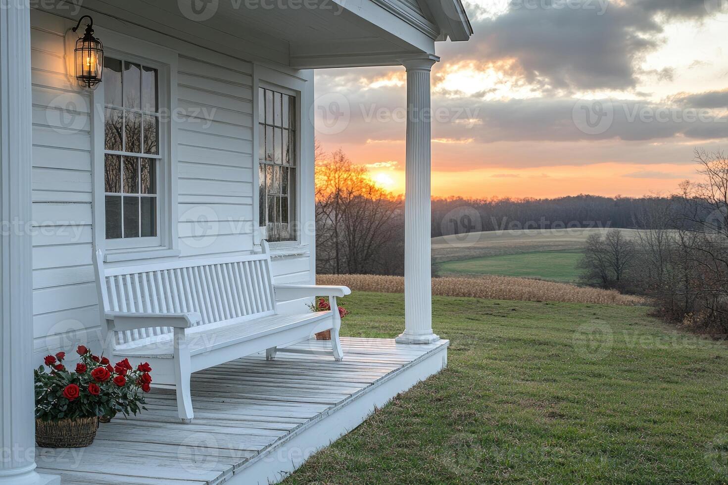 White bench sitting on front porch overlooking sunset on countryside farm photo