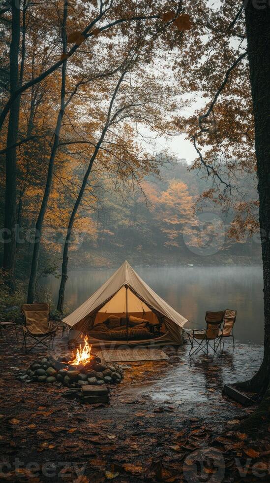 Illuminated tent camping by misty river in autumn forest photo