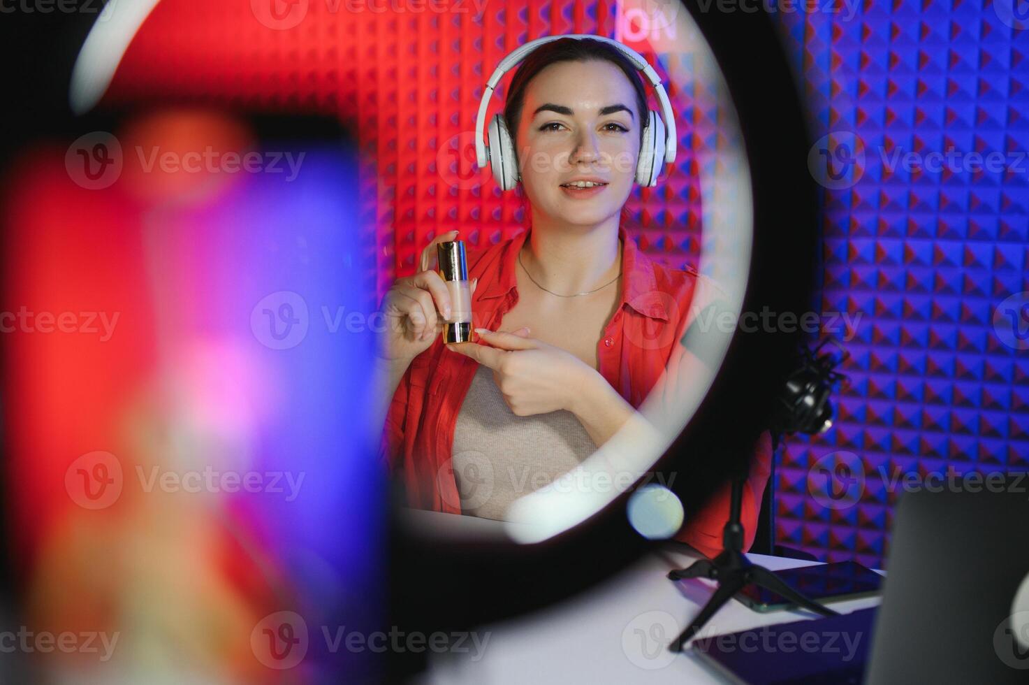Beauty blogger woman filming daily make-up routine tutorial near camera on tripod photo