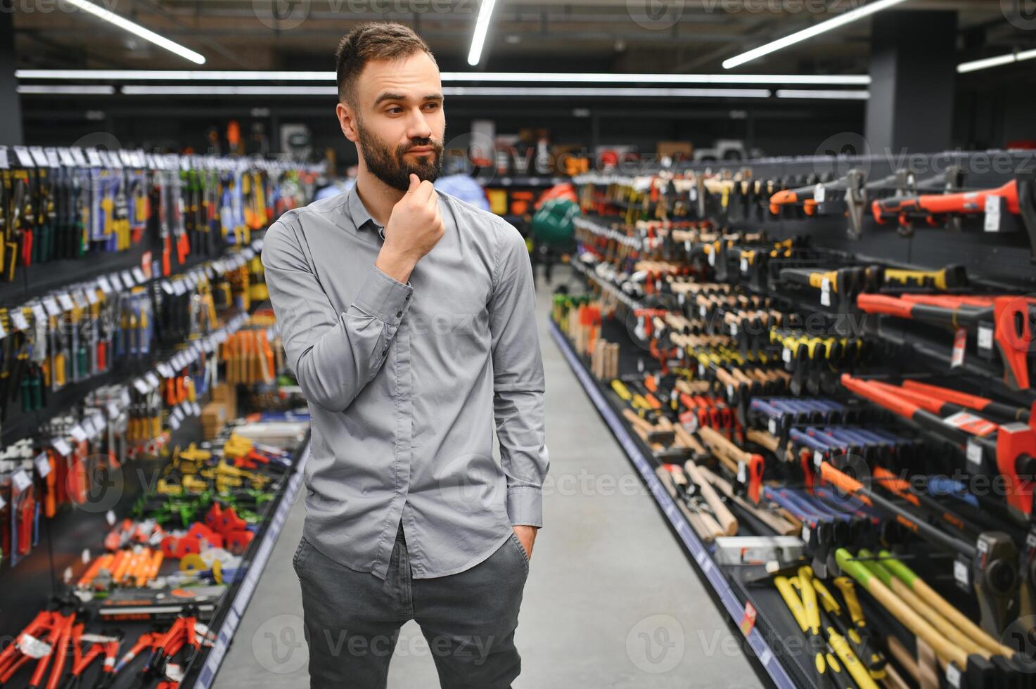 male builder in a hardware store chooses a tools photo