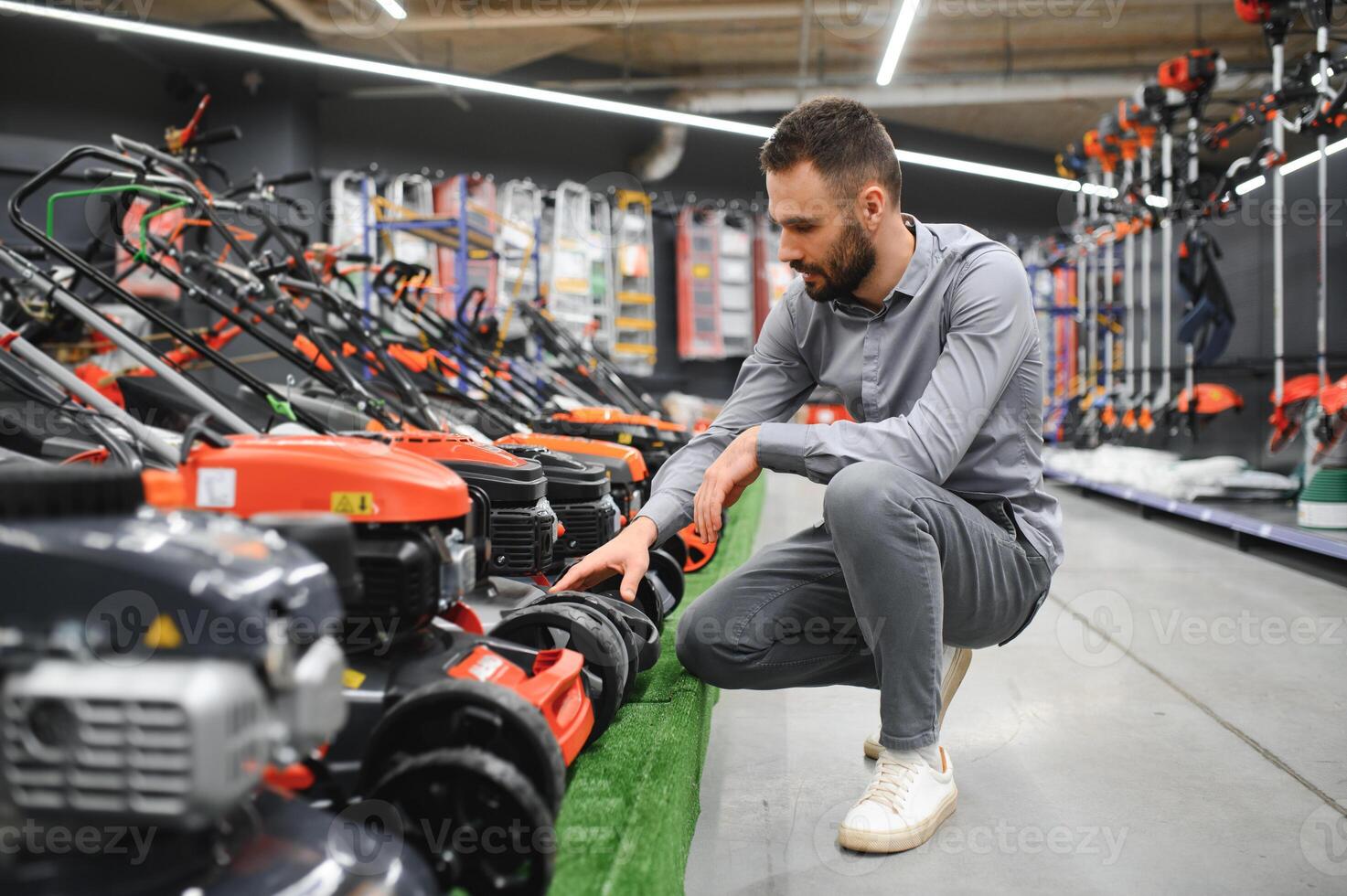 a customer examines new models of lawn mowers in an electrical store for gardeners and horticulturists photo