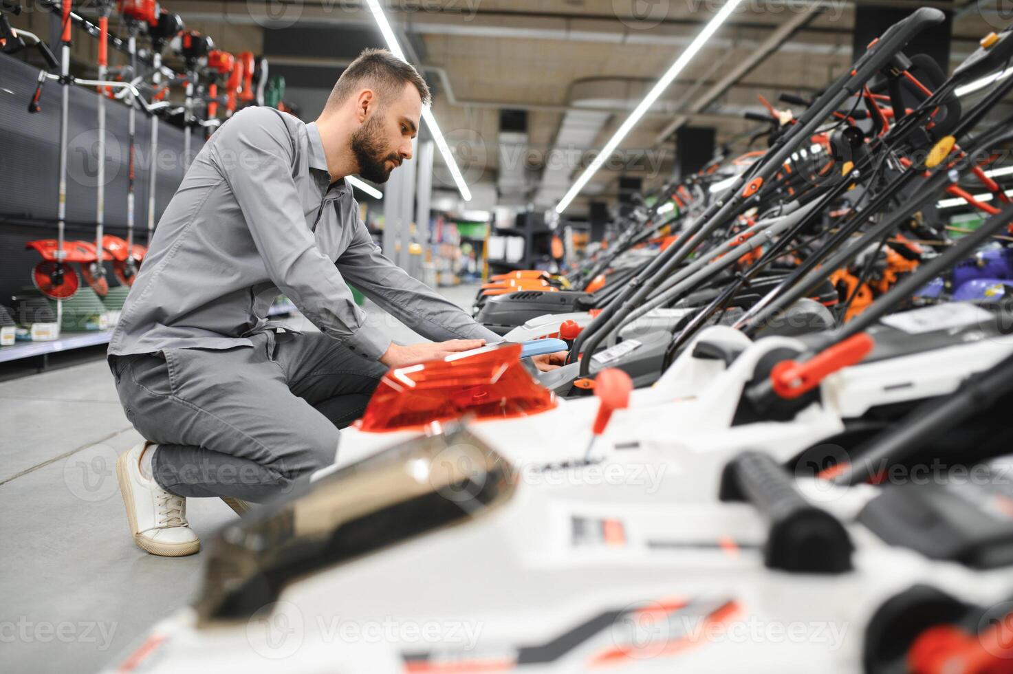a customer examines new models of lawn mowers in an electrical store for gardeners and horticulturists photo