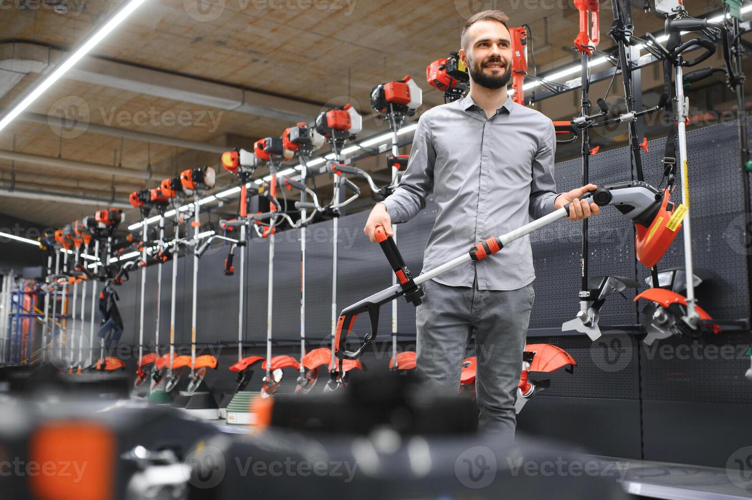 customer with electric lawn trimmer in hands at garden equipment store photo