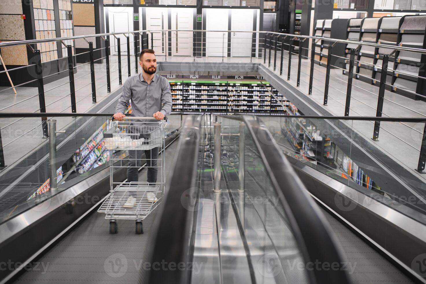 A man with a shopping cart on an escalator in a hardware store. photo