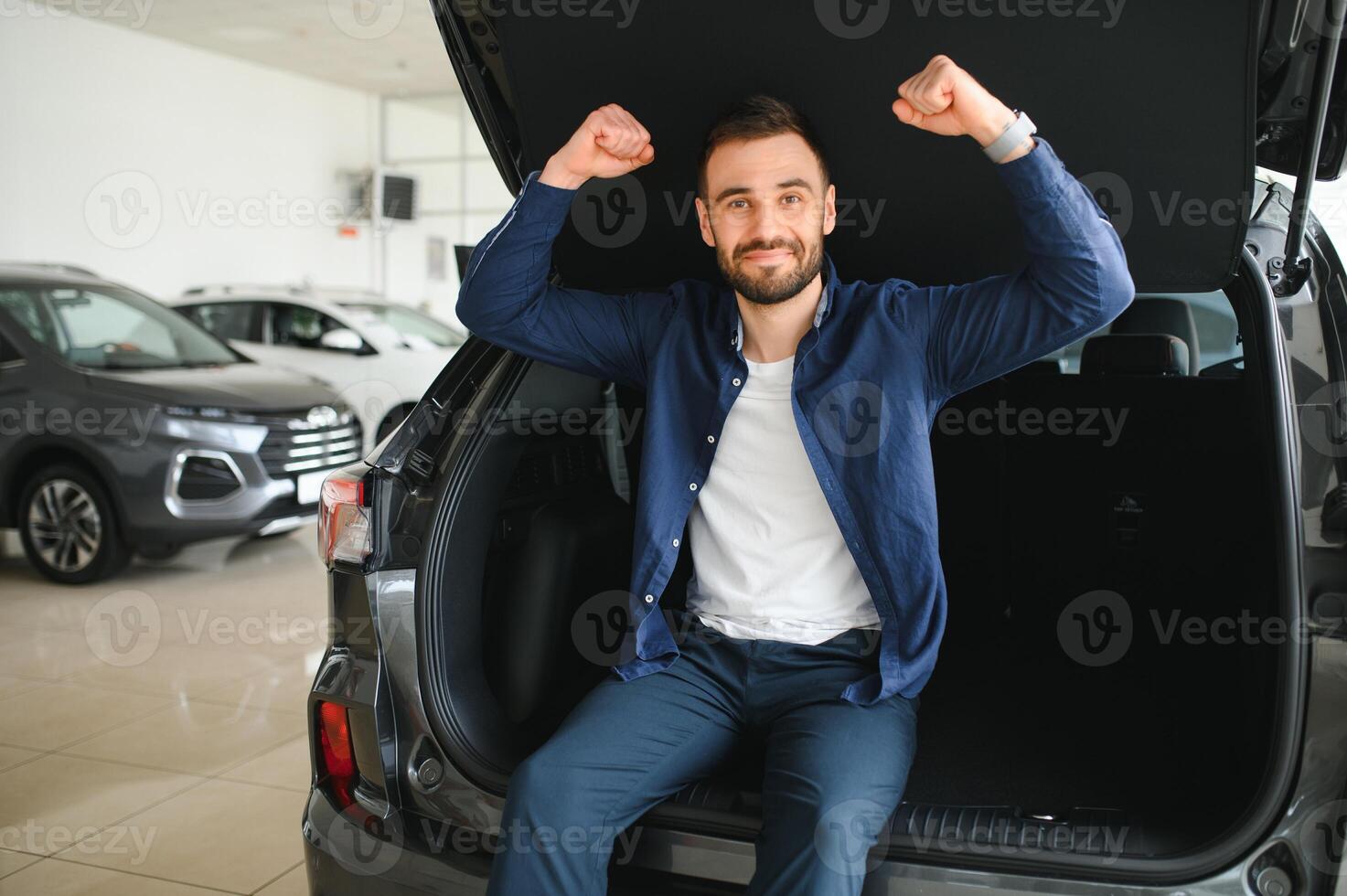 Young man is choosing a new vehicle in car dealership photo