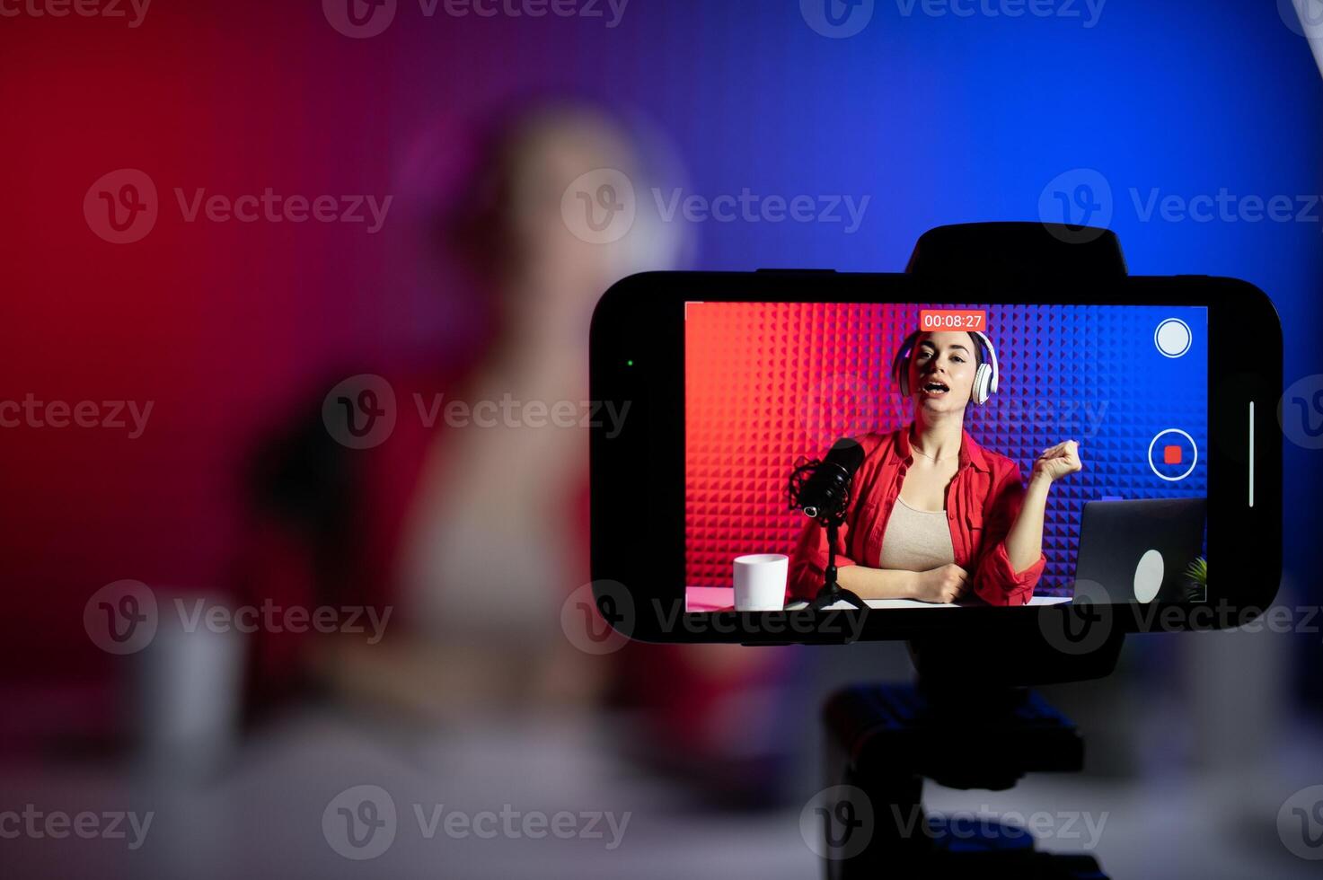 Young attractive woman blogger or vlogger looking at camera and talking on shooting with technology photo