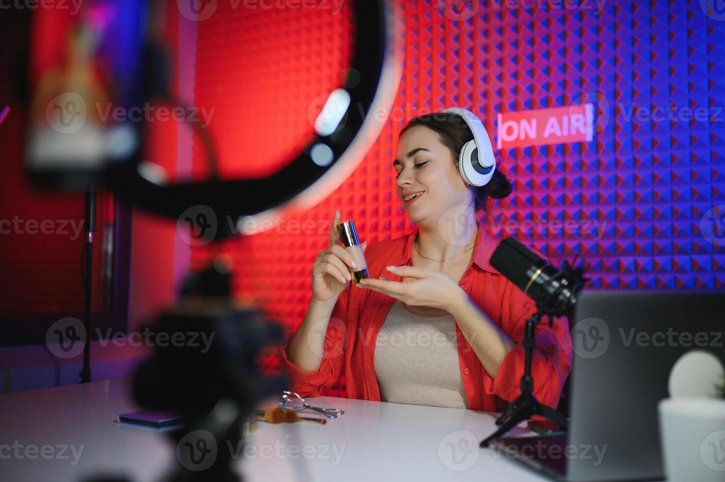 Beauty blogger woman filming daily make-up routine tutorial near camera on tripod photo