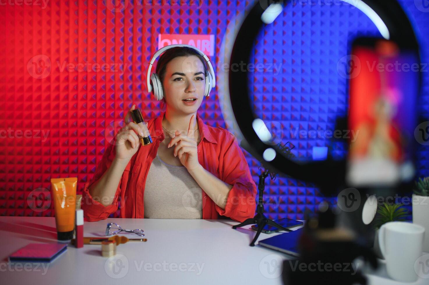 Beauty blogger woman filming daily make-up routine tutorial near camera on tripod photo
