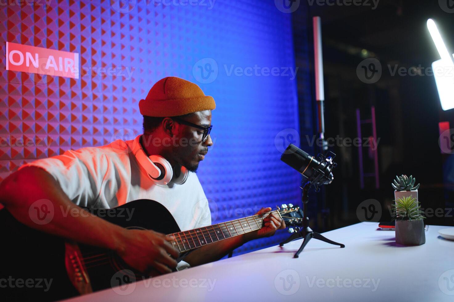 A young stylish music teacher playing guitar in front of smartphone camera. Online guitar training or vocal lesson photo