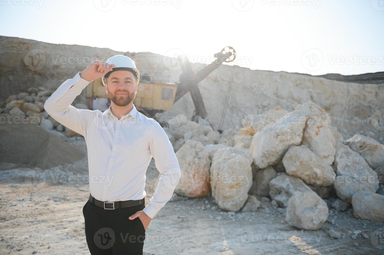 Worker in hardhat standing in stone quarry photo