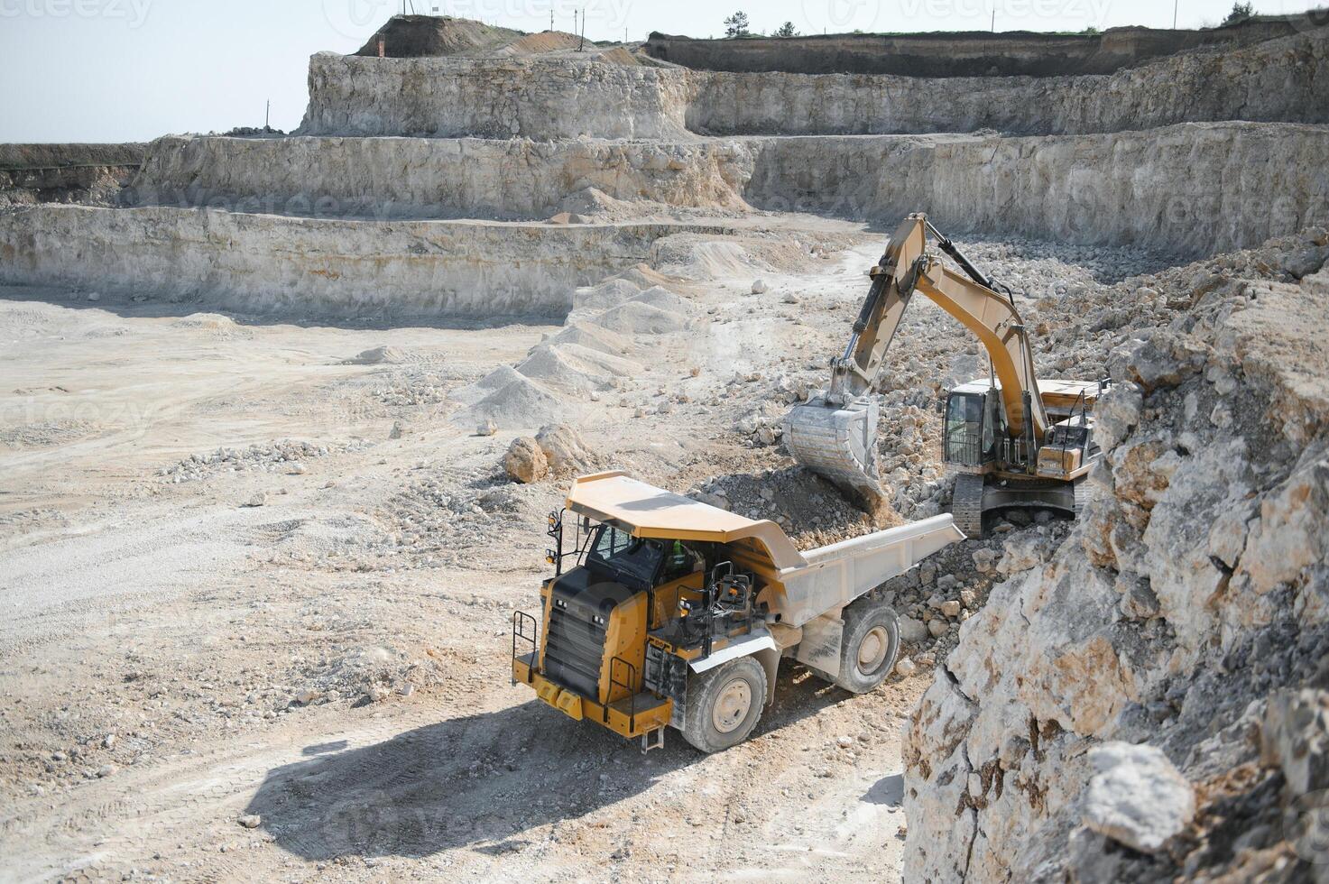 Heavy mining truck and excavator, close-up, against the background of the panorama of a limestone quarry photo