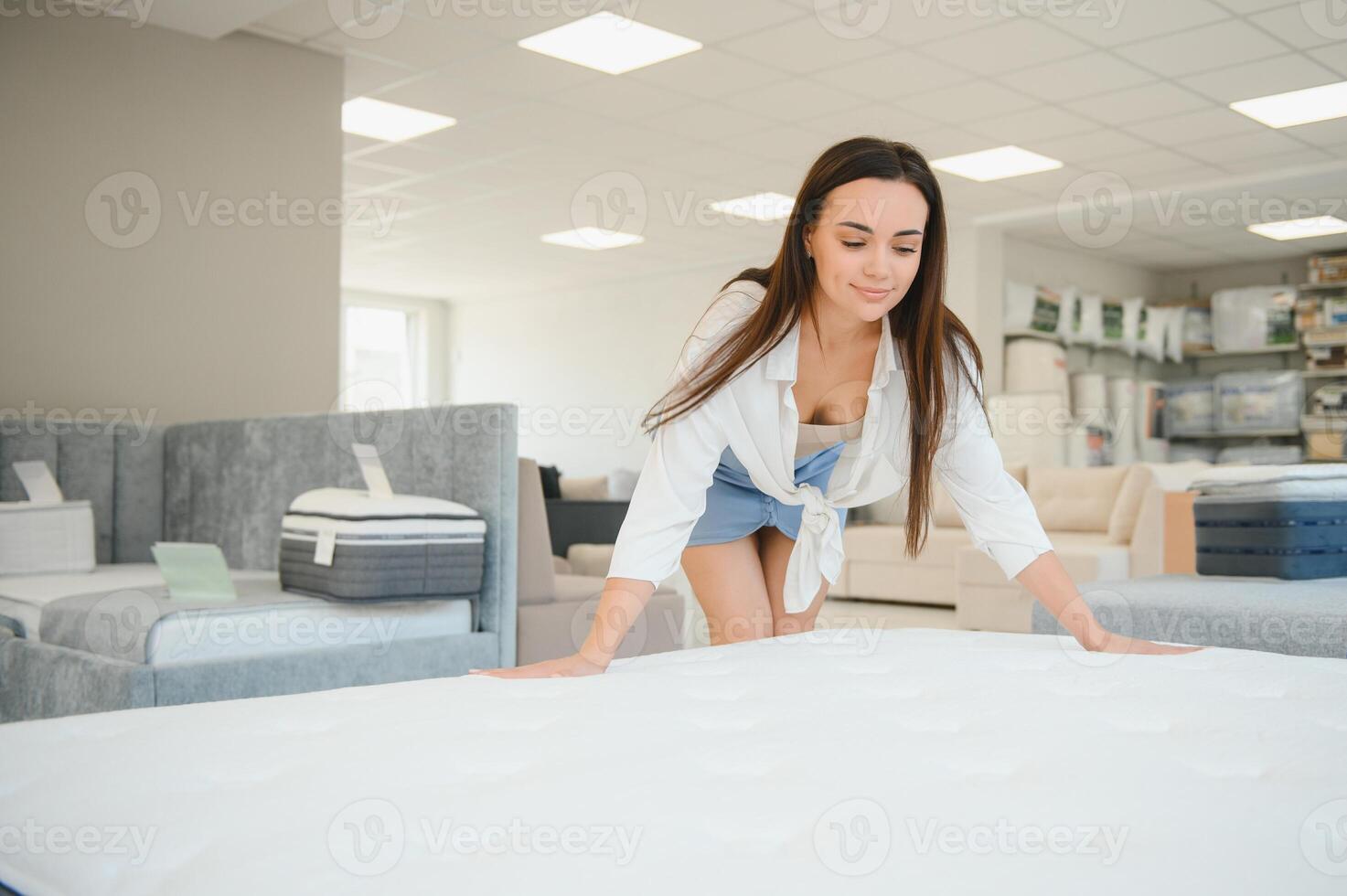 A woman in a white shirt in a mattress store. She examines the mattress she wants to buy photo