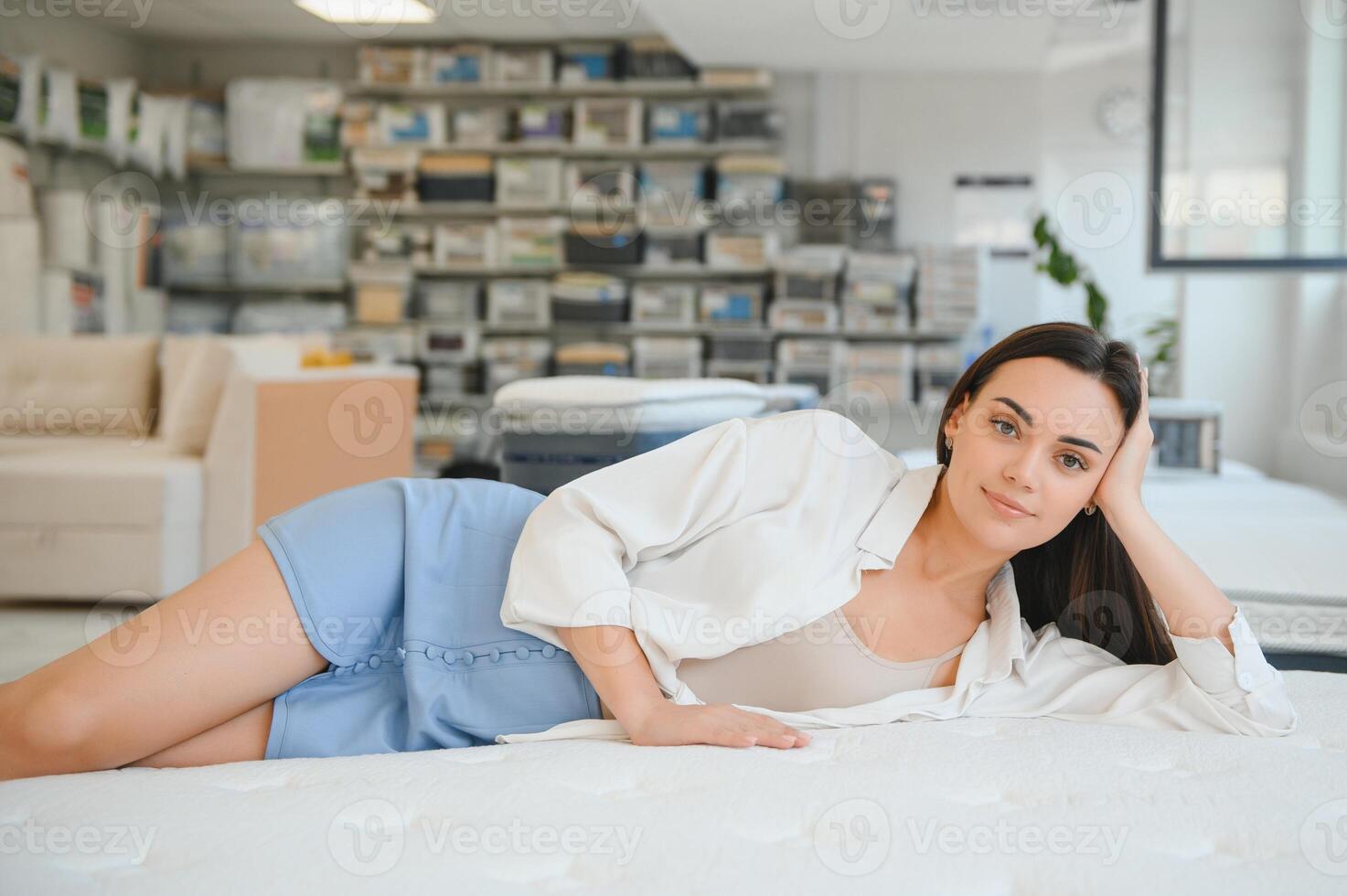 A woman in a white shirt in a mattress store. She examines the mattress she wants to buy photo