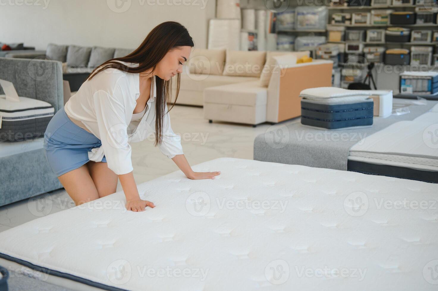 A woman in a white shirt in a mattress store. She examines the mattress she wants to buy photo