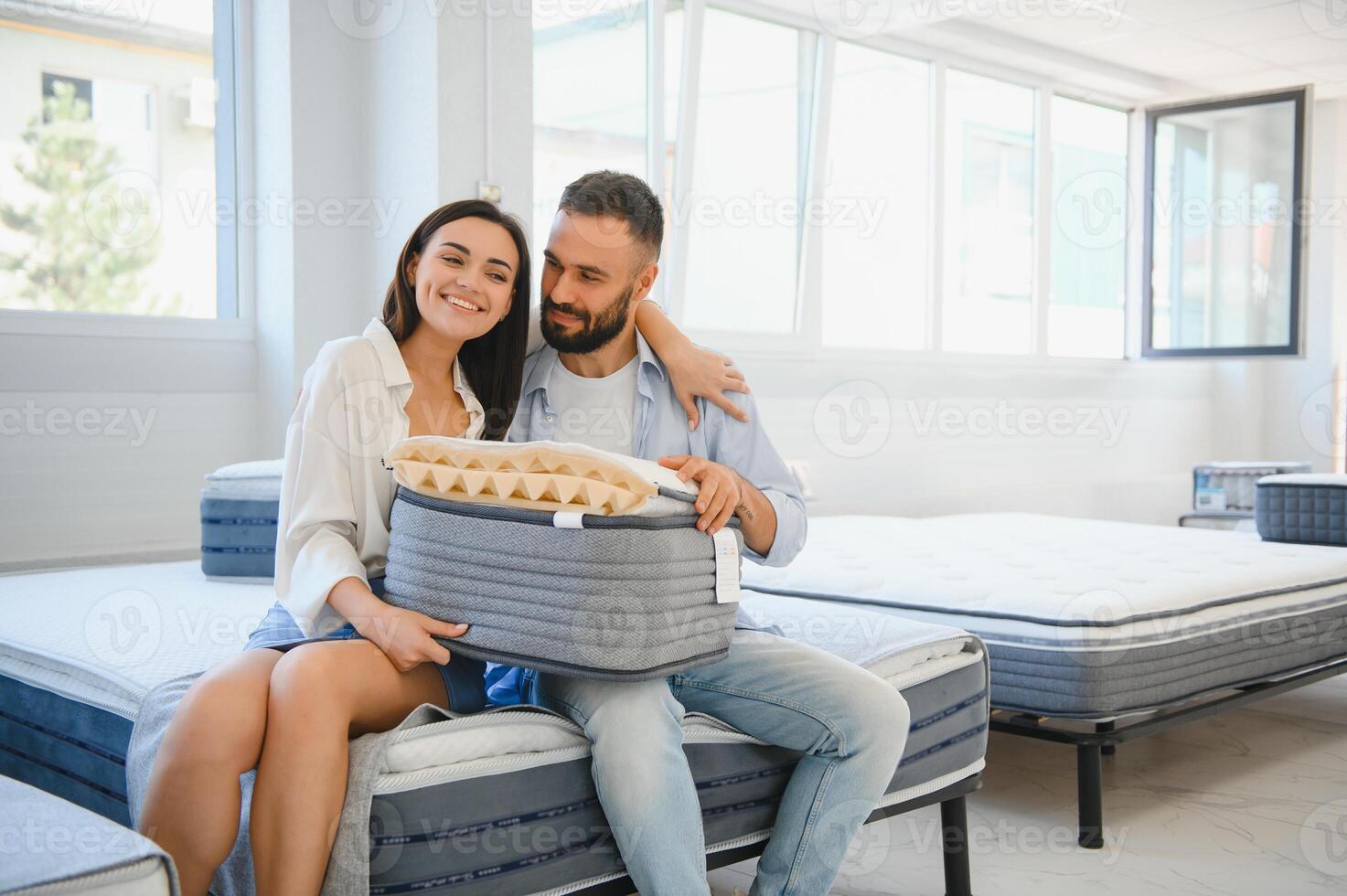 A married couple chooses a new bed for the bedroom and an orthopedic mattress in a furniture store photo
