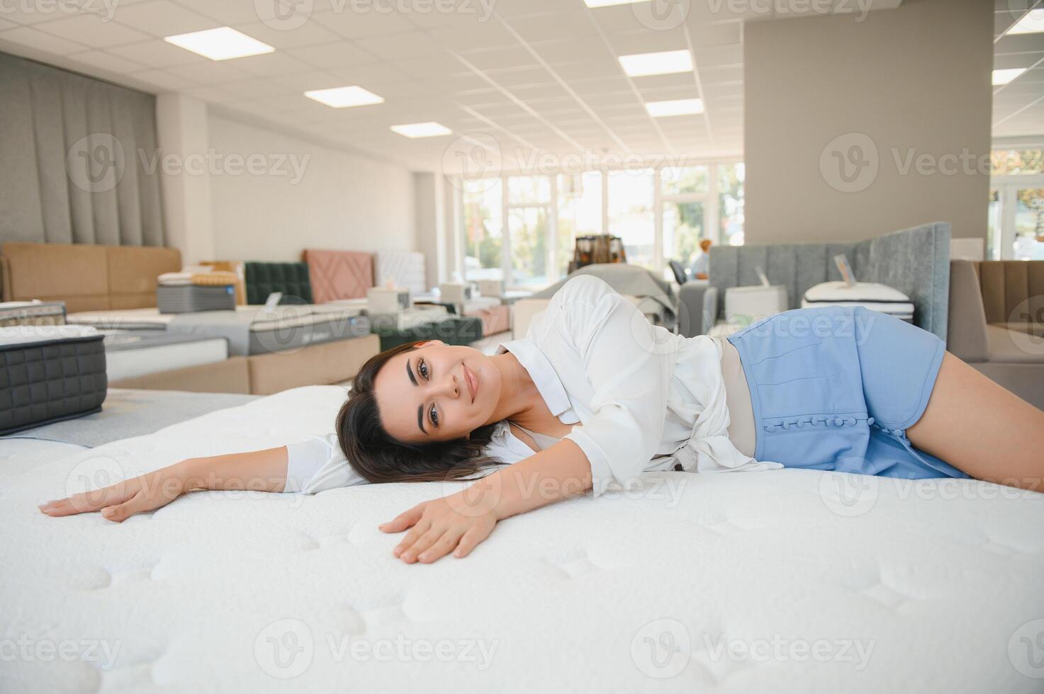 Beautiful young woman relaxing on orthopedic mattress. Healthy sleep, rest concept photo