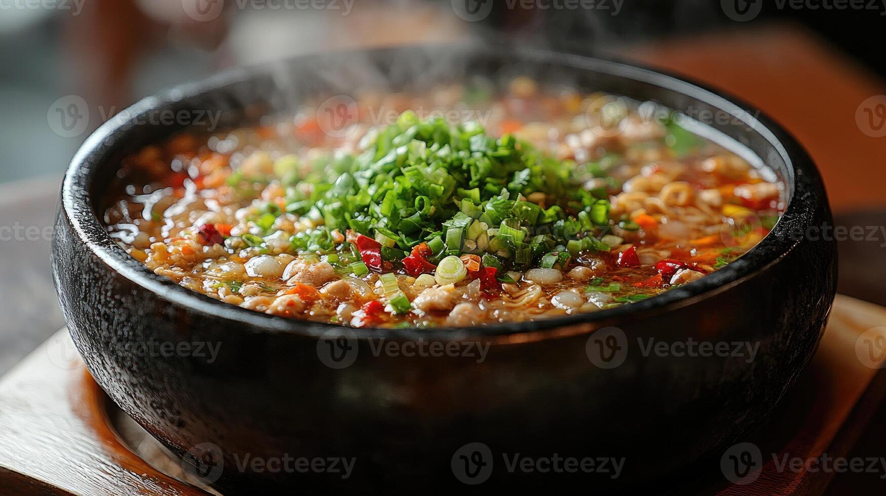 Spicy korean food dakgalbi steaming in a hot stone bowl photo