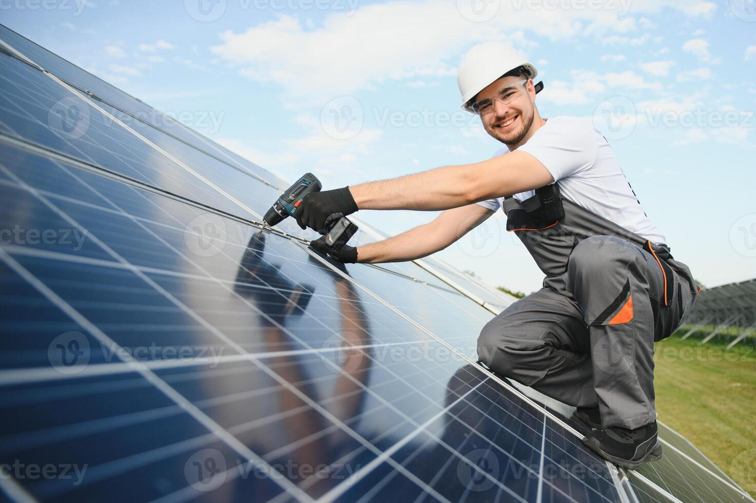 Portrait of a worker in uniform and white helmet working on solar panels photo