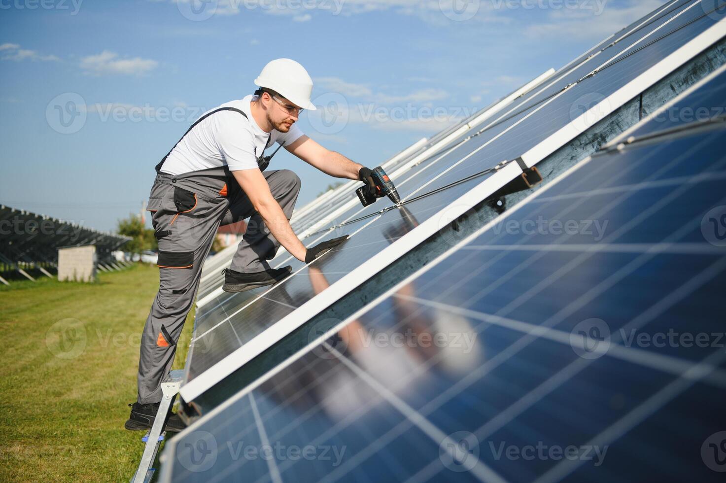 Portrait of a worker in uniform and white helmet working on solar panels photo