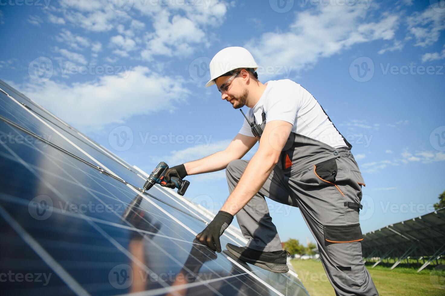 Man technician mounting photovoltaic solar moduls. Engineer in helmet installing solar panel system outdoors photo