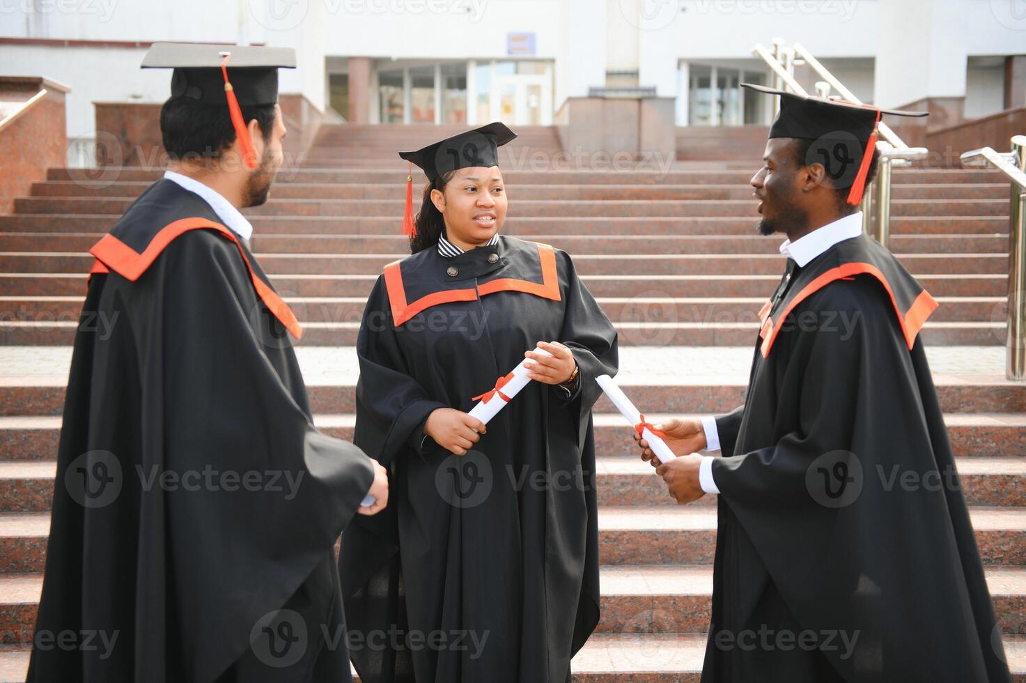 education, graduation and people concept - group of happy international students in mortar boards and bachelor gowns with diplomas photo