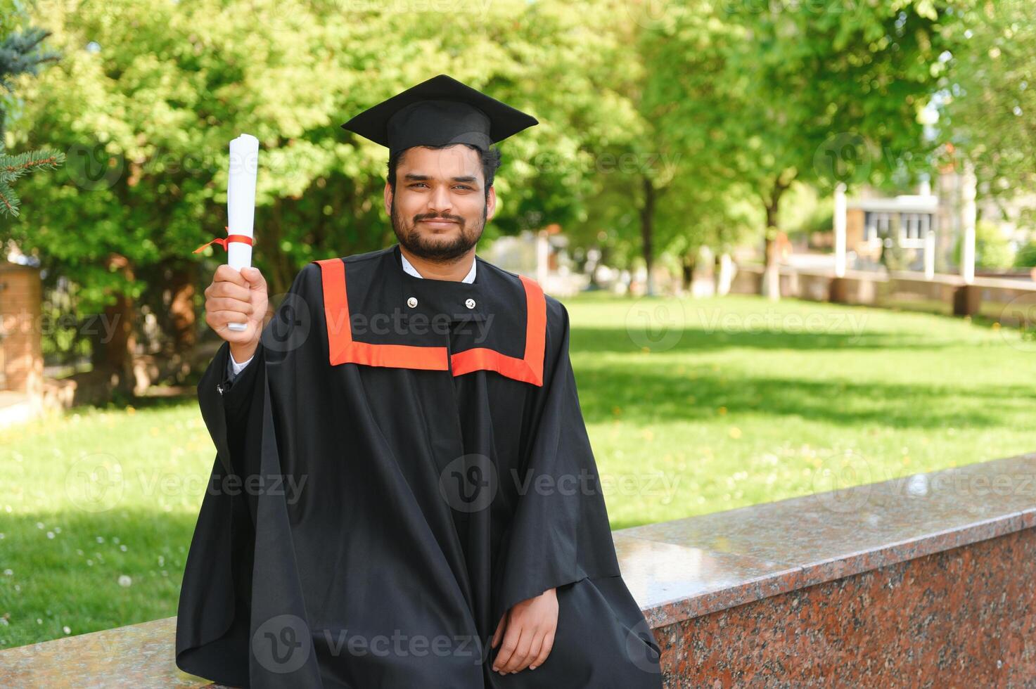Handsome indian graduate in graduation glow with diploma photo