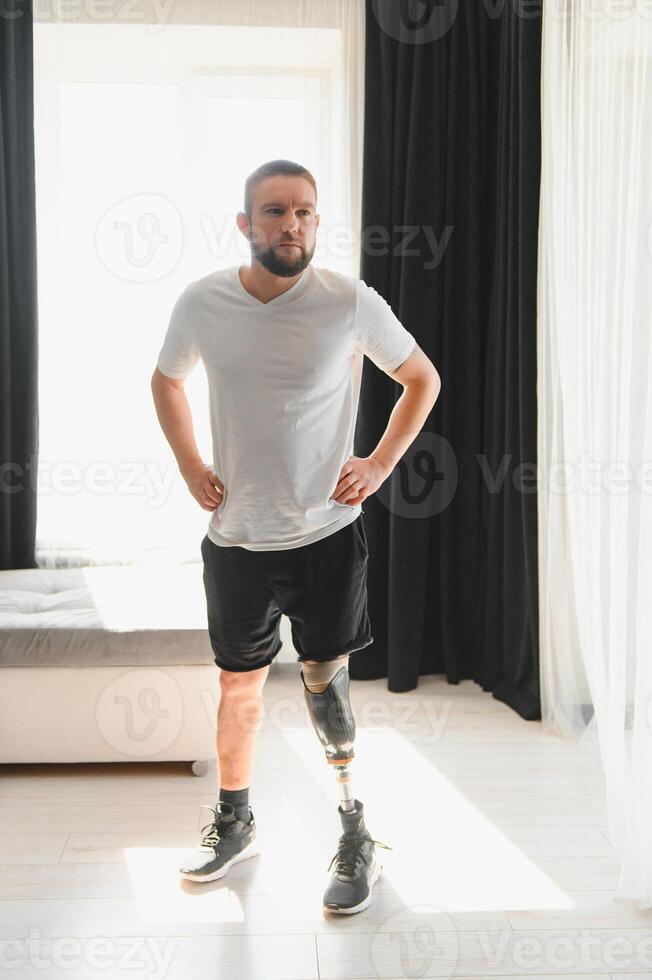 Man amputee with prosthetic leg disability on above knee transfemoral leg prosthesis artificial device at home. People with amputation disabilities everyday life photo