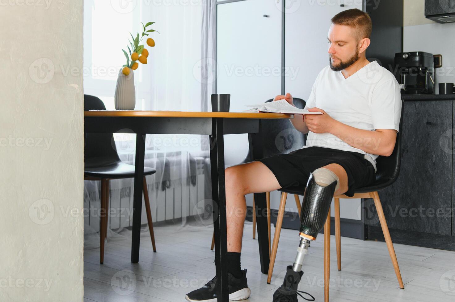 Portrait of man with prosthetic leg reading book while relaxing at home, copy space photo