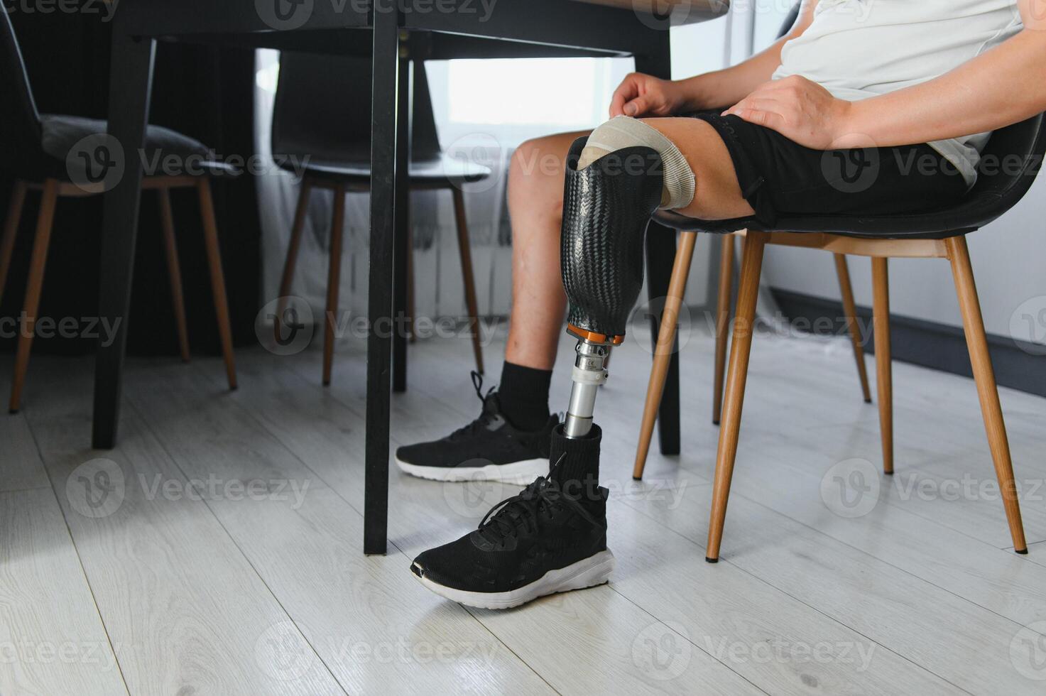 Closeup of unrecognizable man with bionic prosthetic leg at home indoors, copy space photo