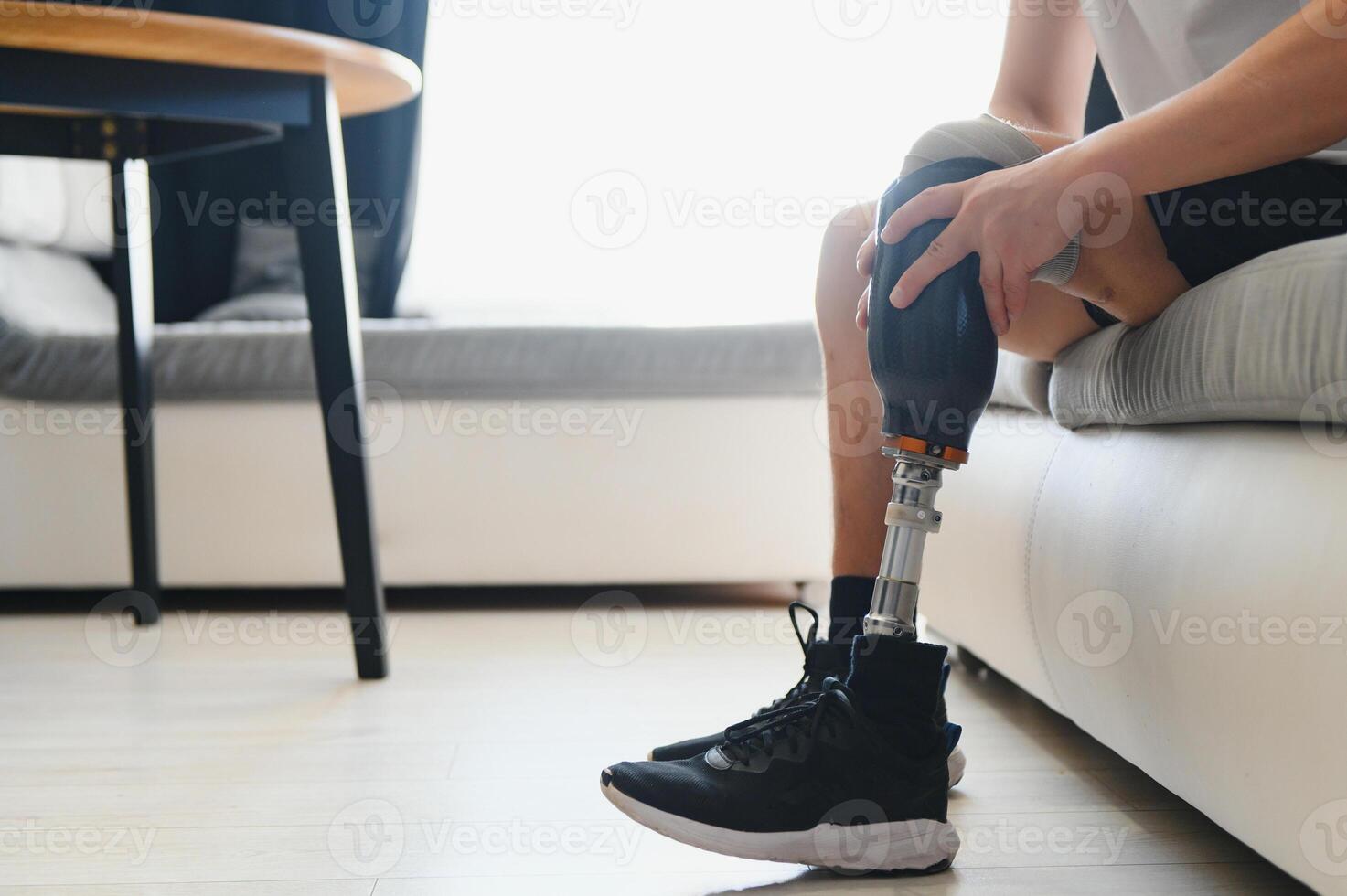 A young man puts on a prosthetic leg at home. Amputation and use of an artificial leg photo