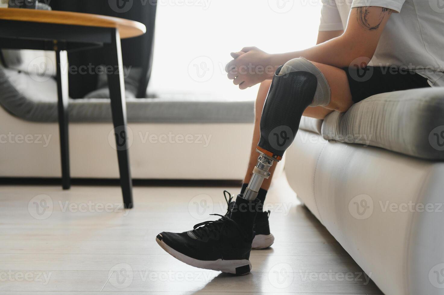 Closeup of unrecognizable man with bionic prosthetic leg at home indoors, copy space photo
