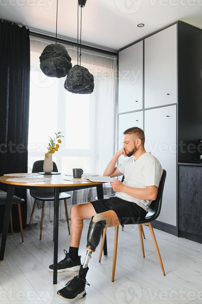 Portrait of man with prosthetic leg reading book while relaxing at home, copy space photo