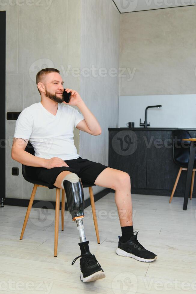 Man amputee with prosthetic leg disability on above knee transfemoral leg prosthesis artificial device at home. People with amputation disabilities everyday life photo