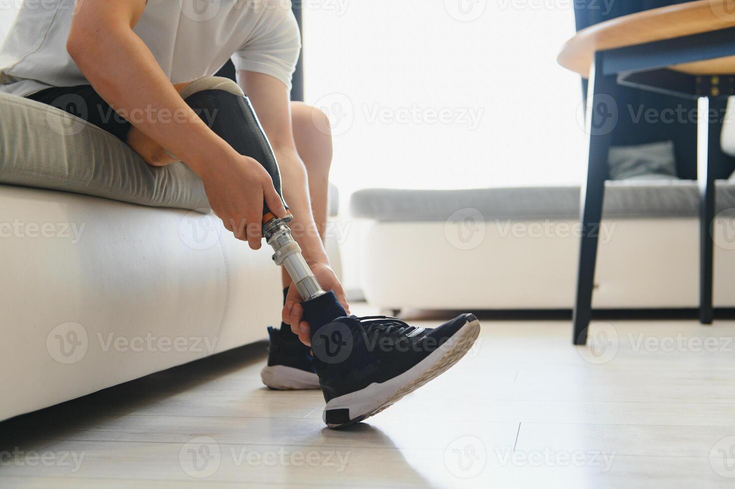 Closeup of unrecognizable man with bionic prosthetic leg at home indoors, copy space photo