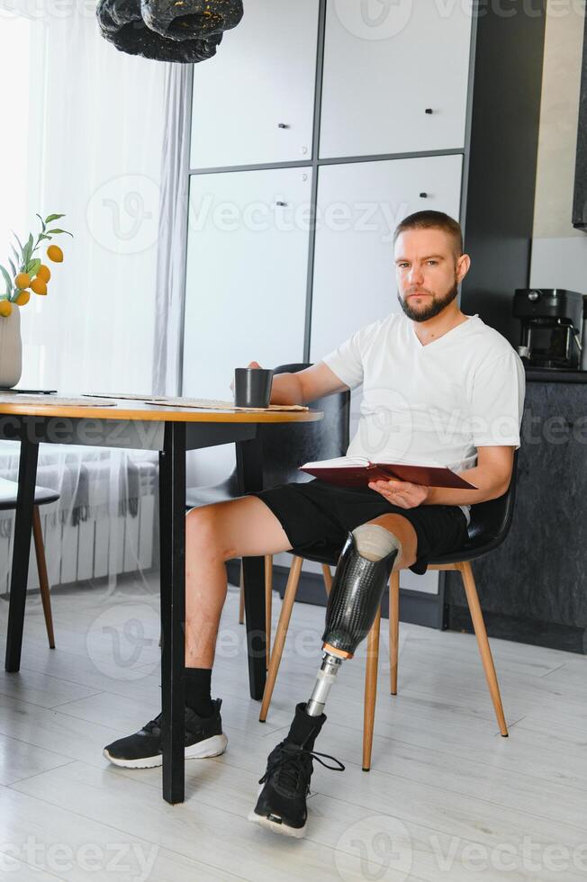 Portrait of man with prosthetic leg reading book while relaxing at home, copy space photo