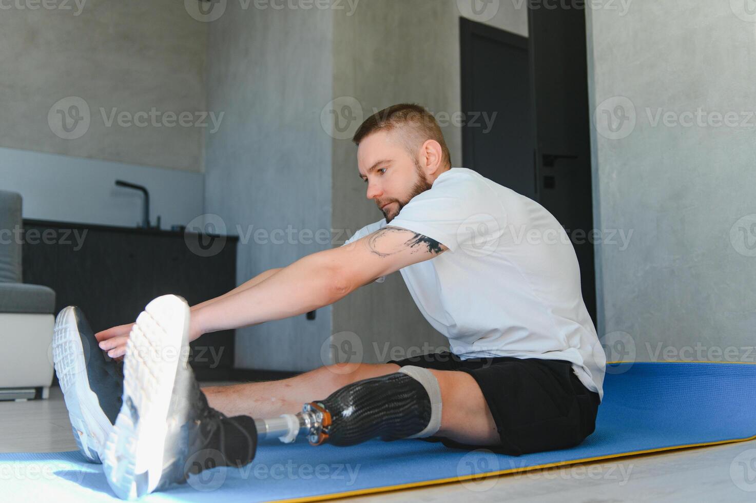 man exercising online stretching his legs at home, with amputated leg prosthesis photo