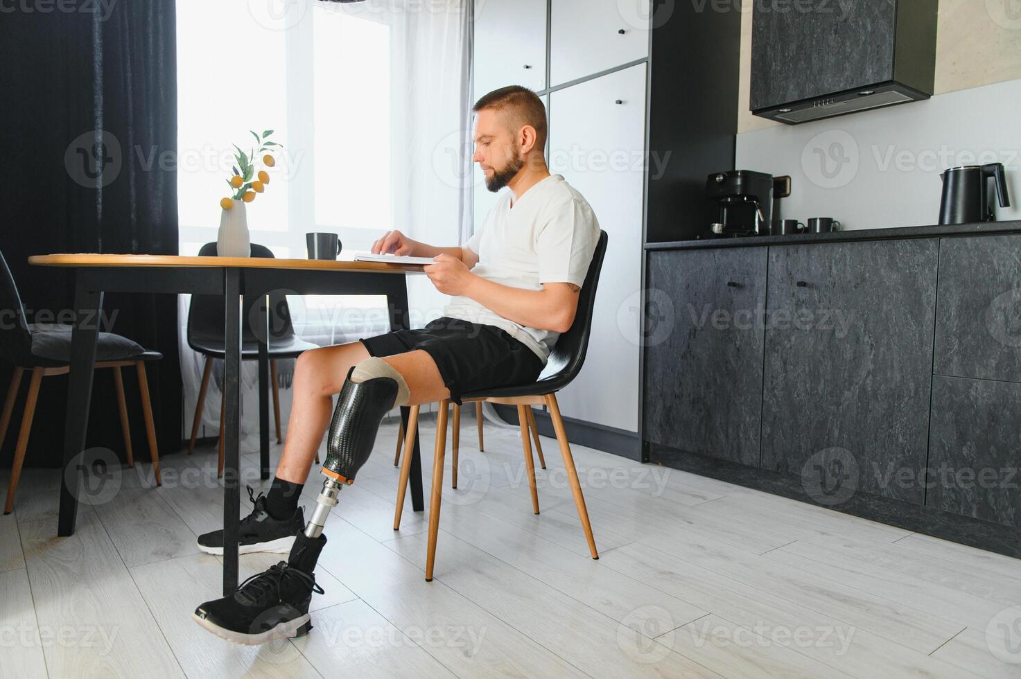 Portrait of man with prosthetic leg reading book while relaxing at home, copy space photo
