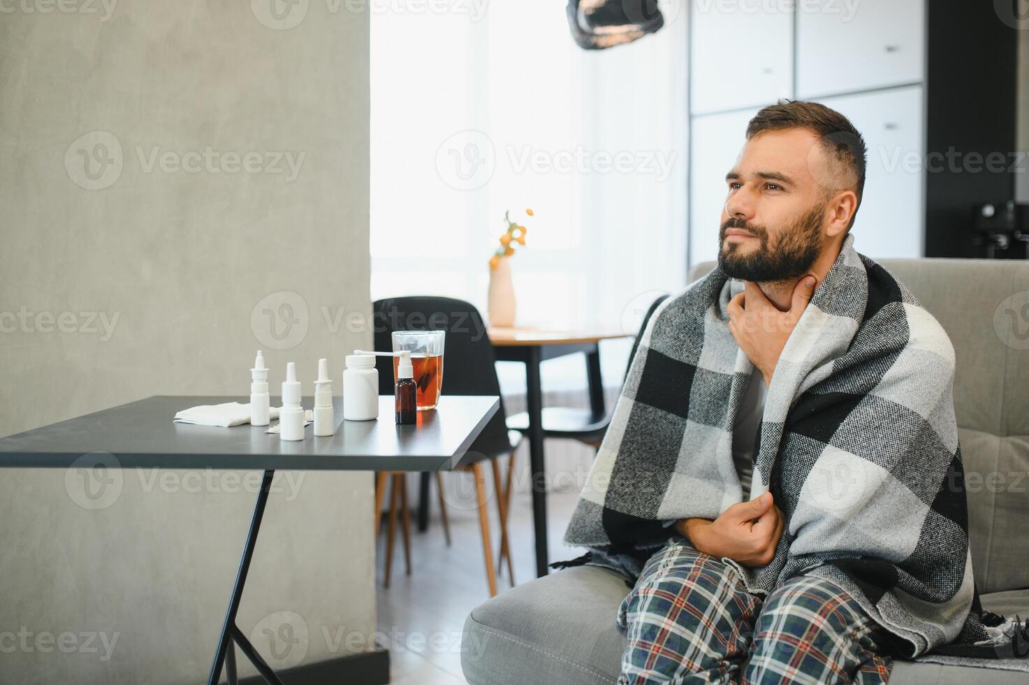 Sick man holding his chest in pain while coughing in the living room. Sore throat and cough, man with lung pain at home, health problems concept photo