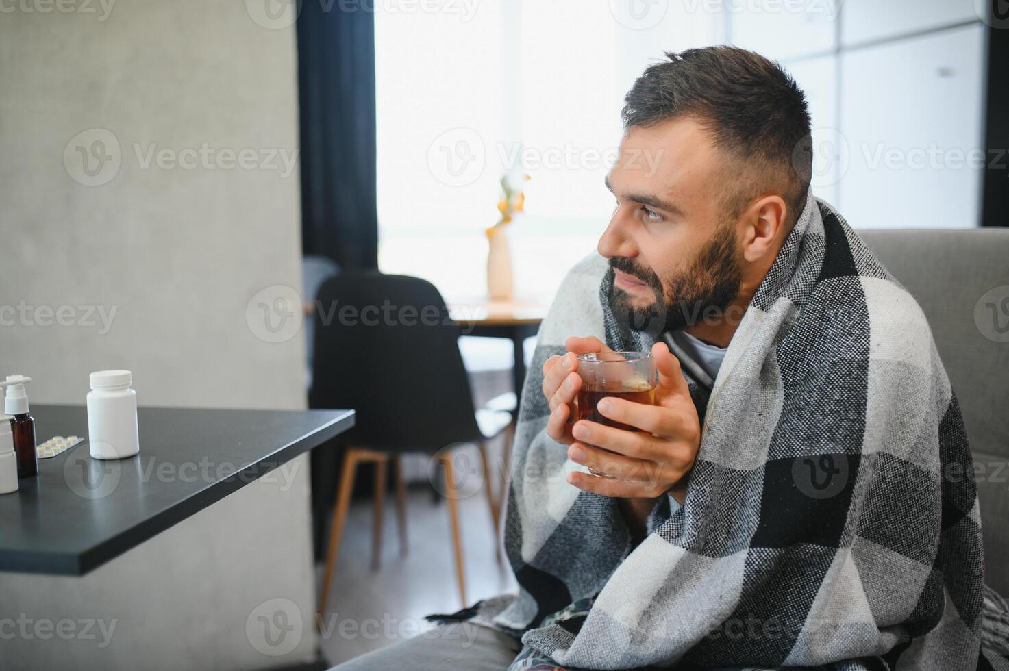 Sick man at home. Young man sitting on sofa having fever photo