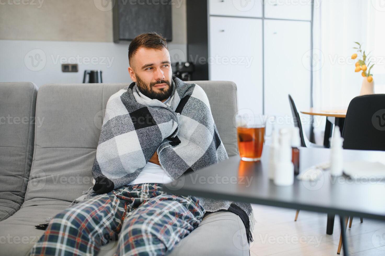 Sick man at home. Young man sitting on sofa having fever photo